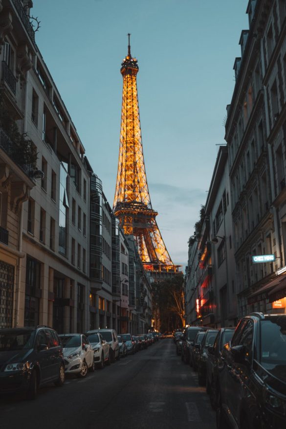 photo of cars parked on side of street across the eiffel tower