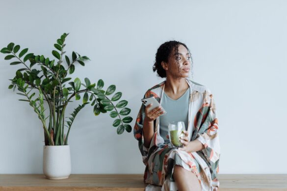 photo of woman sitting beside an indoor plant