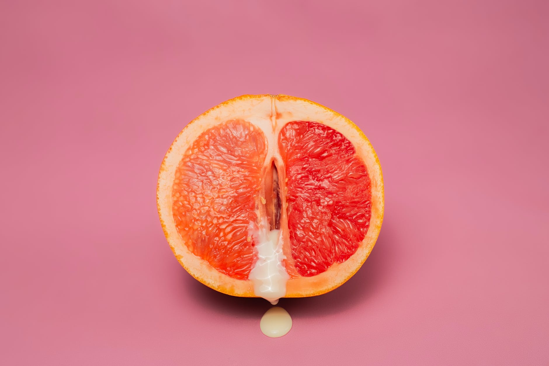 sexy grapefruit with sperm against pink background