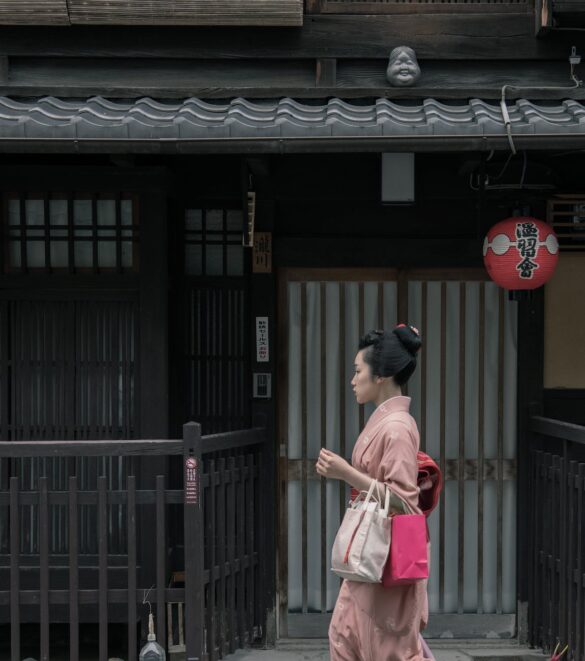 woman wearing pink kimono walking near houses