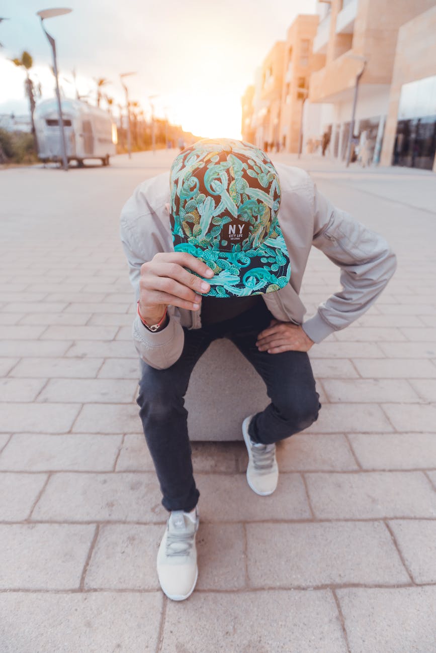 man in black and green floral ny cap sitting on concrete bench