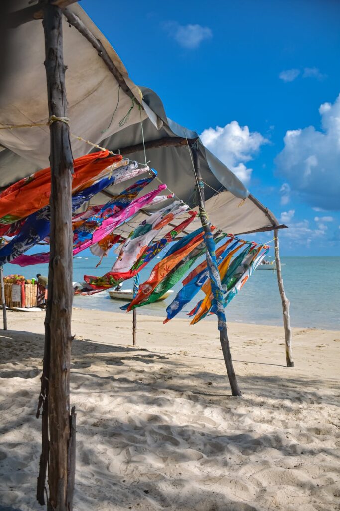 colorful scarves hanging on a line under pavilions on a beach