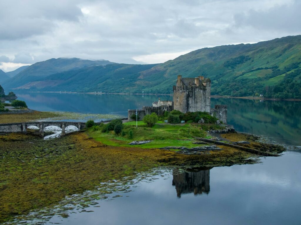 an aerial shot of a castle beside a lake