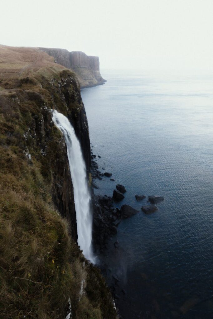 amazing waterfall streaming through rocky cliff and emptying into ocean